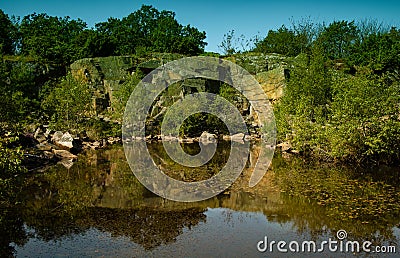 Pond surrounded by rocks and greenery Stock Photo