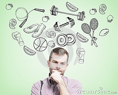 Pondering handsome man in casual clothes is thinking about his choice of sport activity. Stock Photo