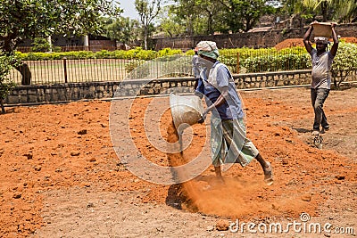 Indian men at work with seal to move the orange earth to cultivate food vegetables grass Editorial Stock Photo