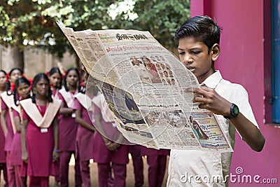 Documentary editorial image. Young man with uniform reads newspaper in the school Editorial Stock Photo
