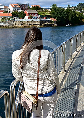 River with woman resting on a handrail and looking at the view. Galicia, Pontevedra, Spain. Stock Photo