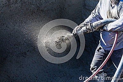 Pool Construction Worker Shooting Concrete, Shotcrete or Gunite Through Hose Stock Photo