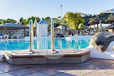 at the pool edge at resort hotel with ladder into the water besides some rocks Editorial Stock Photo