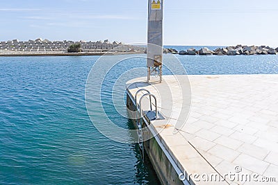 Pool ladder on a white marble pier in front of a sign forbidden to climb the tower due to danger of electrocution Editorial Stock Photo