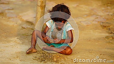 poor alone baby girl playing in soil Editorial Stock Photo
