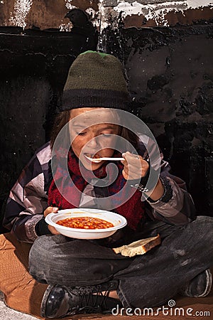 Poor beggar child eating charity food Stock Photo