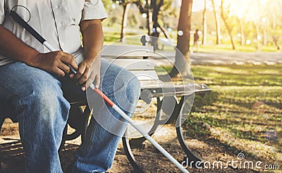 The poor blind Asian elder brother sat calmly holding a blind cane. sit on the bench tired Stock Photo