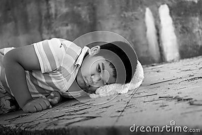 Poor boy sad lying on the dirty floor Stock Photo