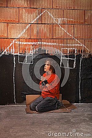 Poor homeless beggar boy praying for a shelter concept Stock Photo