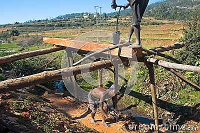 Poor malagasy men cutting timber Editorial Stock Photo