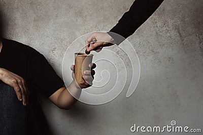 Poor man receiving coin from woman Stock Photo