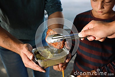 Poor people receiving food from volunteer outdoors Stock Photo