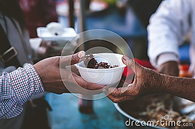 Poor people's hands share free food from volunteers who donate food : concept of feeding, sharing food Stock Photo