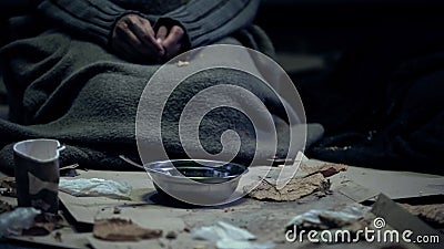 Poor person in dirty cloth sitting front of bowl, living on street, homelessness Stock Photo