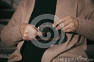 Poor senior woman with empty wallet and coin indoors Stock Photo