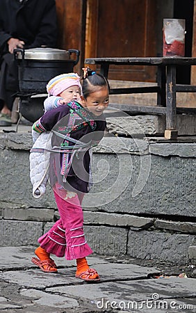 Poor traditional girl who care kid in the old village in China Editorial Stock Photo