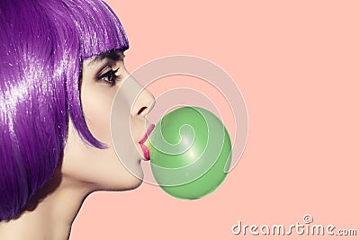 Pop art woman blowing bubble gum. Side view on pink background. Stock Photo