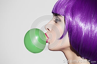 Pop art woman portrait wearing purple wig. Blow a green bubble Stock Photo