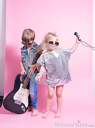 Pop Culture: Children a boy with a guitar and a girl with a microphone pretend to be popular musicians and perform a Stock Photo