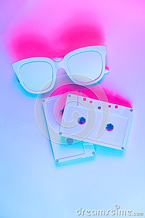 Pop culture, retrowave. Audio cassette on glowing duotone background. Neon red blue light. Stock Photo