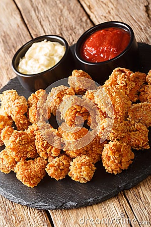 Popcorn chicken is a dish consisting of small bite sized pieces of chicken that have been breaded and fried closeup in the slate Stock Photo