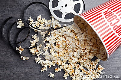 Popcorn and movie reel on grey stone table. Cinema snack Stock Photo