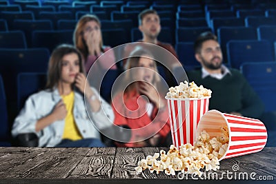 Popcorn on table and young people in cinema hall Stock Photo