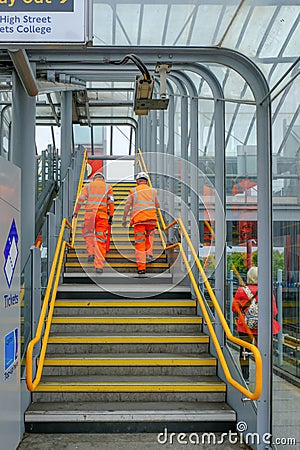 Tow maintenace men climbing up stairs in orange hi-viz clothing Editorial Stock Photo