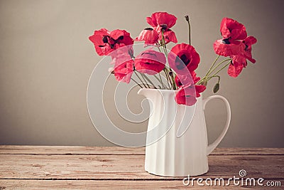 Poppy flower bouquet in white jug on wooden table Stock Photo