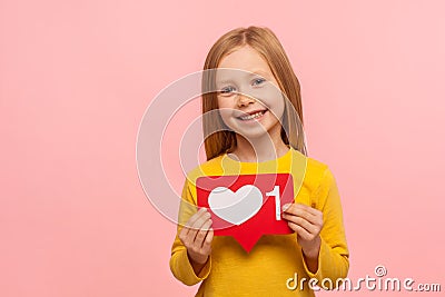 Popular child content, blogging. Portrait of charming preschool girl holding heart like icon of social media Stock Photo