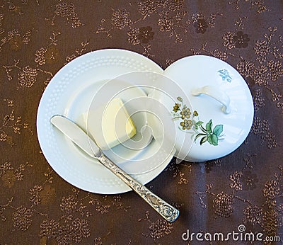 Porcelain plate with cover and silver knife with butter on a decorated cover - top view Stock Photo