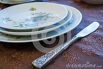 Porcelain plates with decorations with a silver knife on a decorated cover Stock Photo