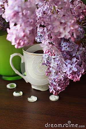 Porcelain teacup, lilac bouquet and white decors Stock Photo