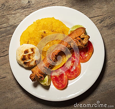 Pork chicharron with patacones and sliced tomatoes - Colombian traditional food Stock Photo