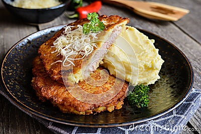 Pork cutlets coated in potato batter, studded with cheese and served with mashed potato Stock Photo