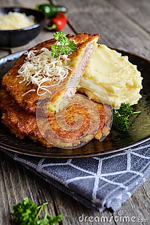 Pork cutlets coated in potato batter, studded with cheese and served with mashed potato Stock Photo