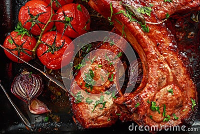 Pork middle chop roast with sweet and sour souce, baked tomatoes and red onion Stock Photo