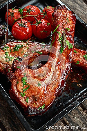 Pork middle chop roast with sweet and sour souce, baked tomatoes and red onion Stock Photo