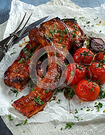 Pork middle chop roast with sweet and sour souce, baked tomatoes and red onion Stock Photo