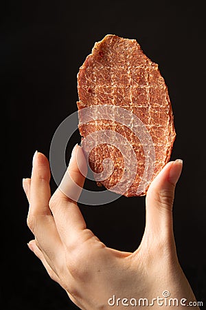 Pork natural jerks in hand on a black background. Stock Photo