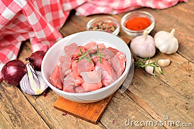 Pork raw meal diced in a bowl, garlic, half of onion, colored and sweet pepper, checkered red tablecloth in the Stock Photo