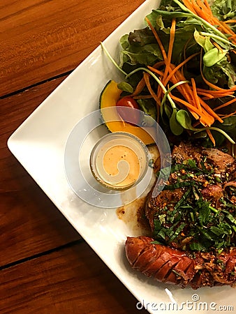 Pork steak and sausage with spicy herbal sauce and salad with dressing in plate pu Stock Photo