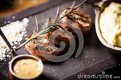 Pork tenderloin with mashed potatos, bacon and mustard sauce with branch of smoking rosemary. Delicious healthy Stock Photo