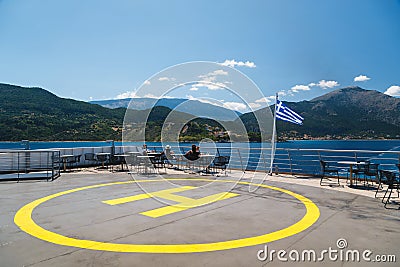 Poros, Cephalonia island, Greece - July, 17 2019: Yellow sign of helipad for helicopters at the ship and passengers relaxing at Editorial Stock Photo