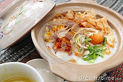 Porridge served on hot claypot topped with chicken, sweet corn, skipjack tuna, tofu, green onions, crackers, dumplings and broth. Stock Photo