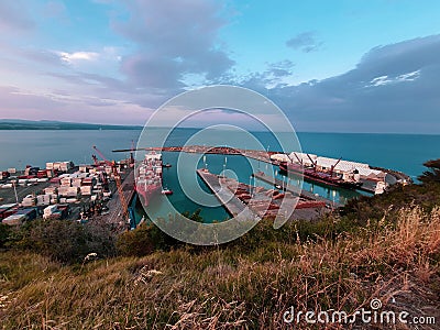 Port bay in Napier New Zealand in sunset on blue water ocean, orange, teal, blue ship cruise cargo containers shipping carry Editorial Stock Photo