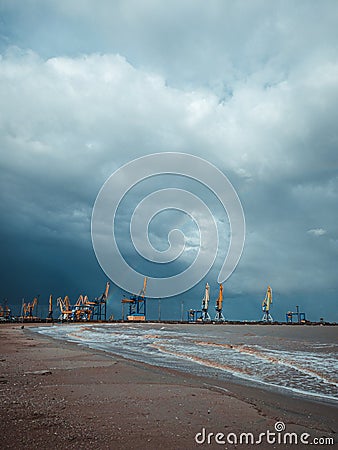 Port cranes under the dark clouds after the thunderstorm. Dramatic stormy sky. Industrial landscape. Idle cranes in front of storm Stock Photo