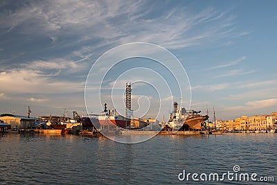 At the port of Mazara del Vallo in Sicily, the port with the shipyard is illuminated golden in the evening sun. There are tender Editorial Stock Photo