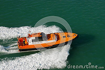 Port pilot on small vessel moving at high speed. Small orange boat shipping on sea water. Pilot boat for guidance into harbor.Equi Editorial Stock Photo