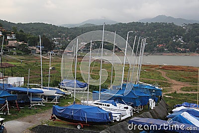 Port of small and large sailboats parked and sailing on the lake of Valle de Bravo in Mexico at sunset Stock Photo